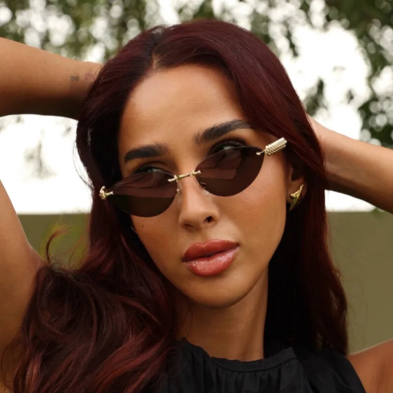 Model wearing narrow black rimless sunglasses for a cyber-siren fashion aesthetic.