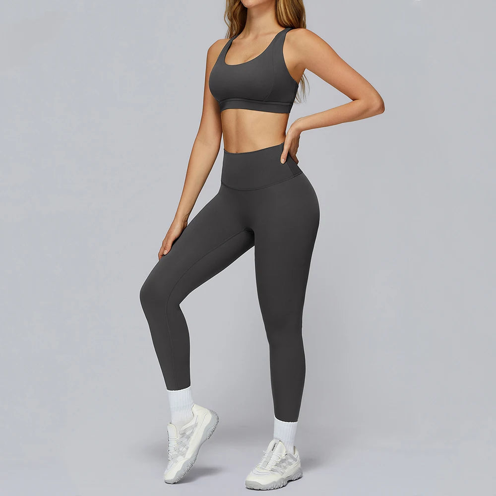 Person wearing a gray sports bra and leggings set on a gray background