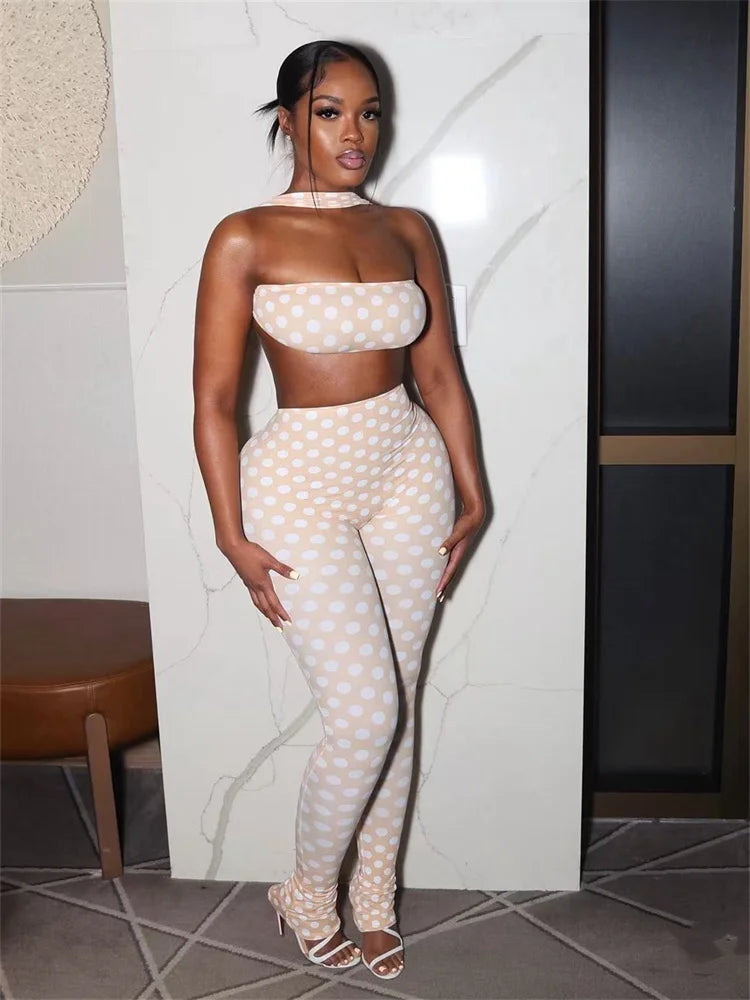 Woman wearing a polka dot outfit standing against a textured wall.
