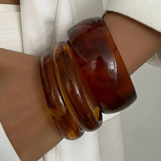 Brown tortoiseshell bangles on a wrist with a neutral background