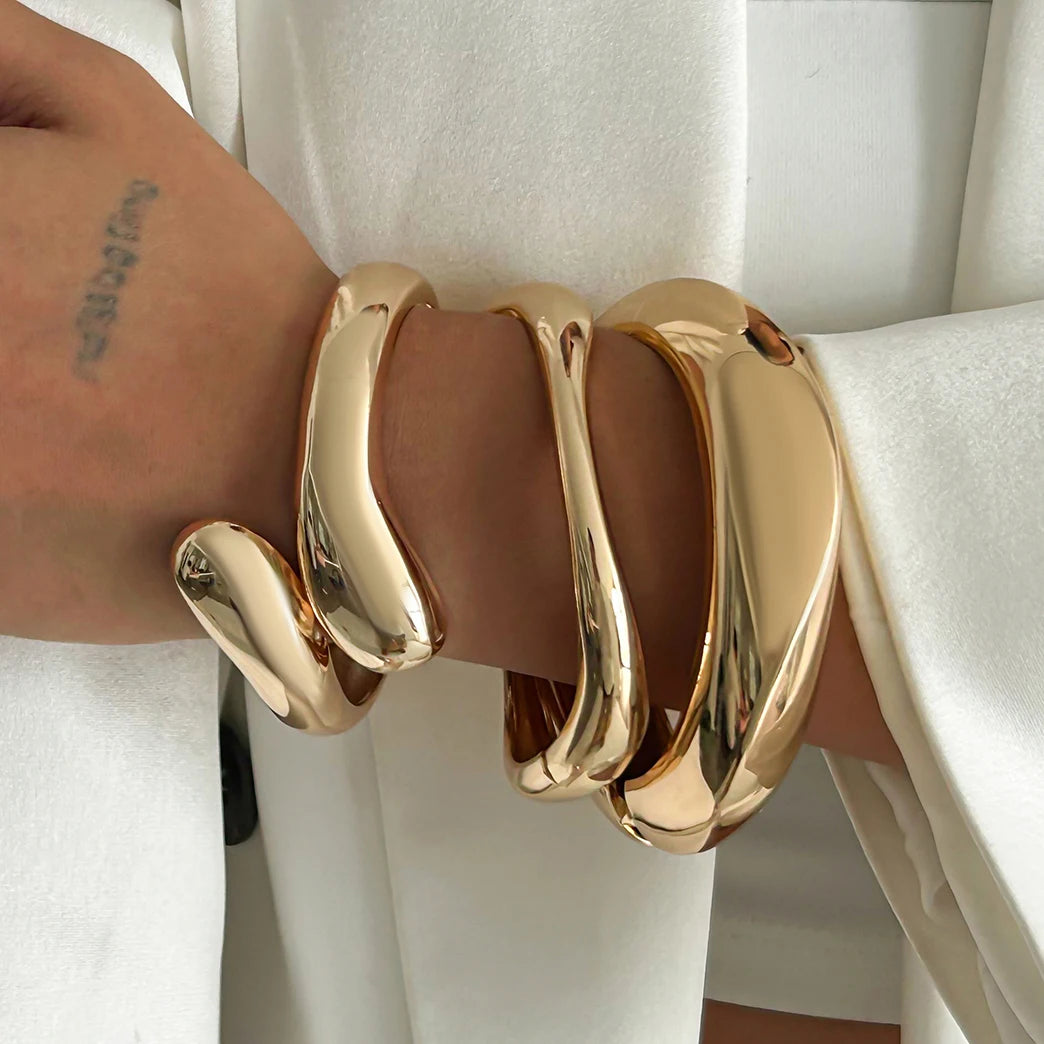 Gold bracelet on a wrist with a white background