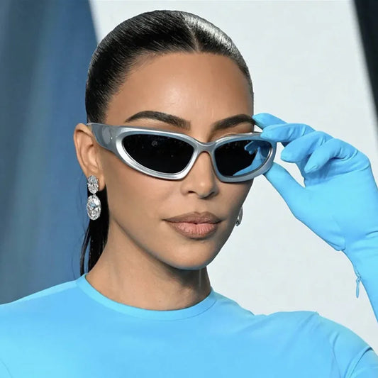 Person wearing sunglasses and a blue glove against a light background