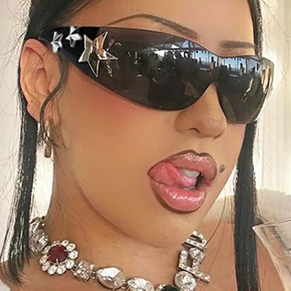 Close-up of a person wearing black sunglasses with star designs and a decorative necklace.