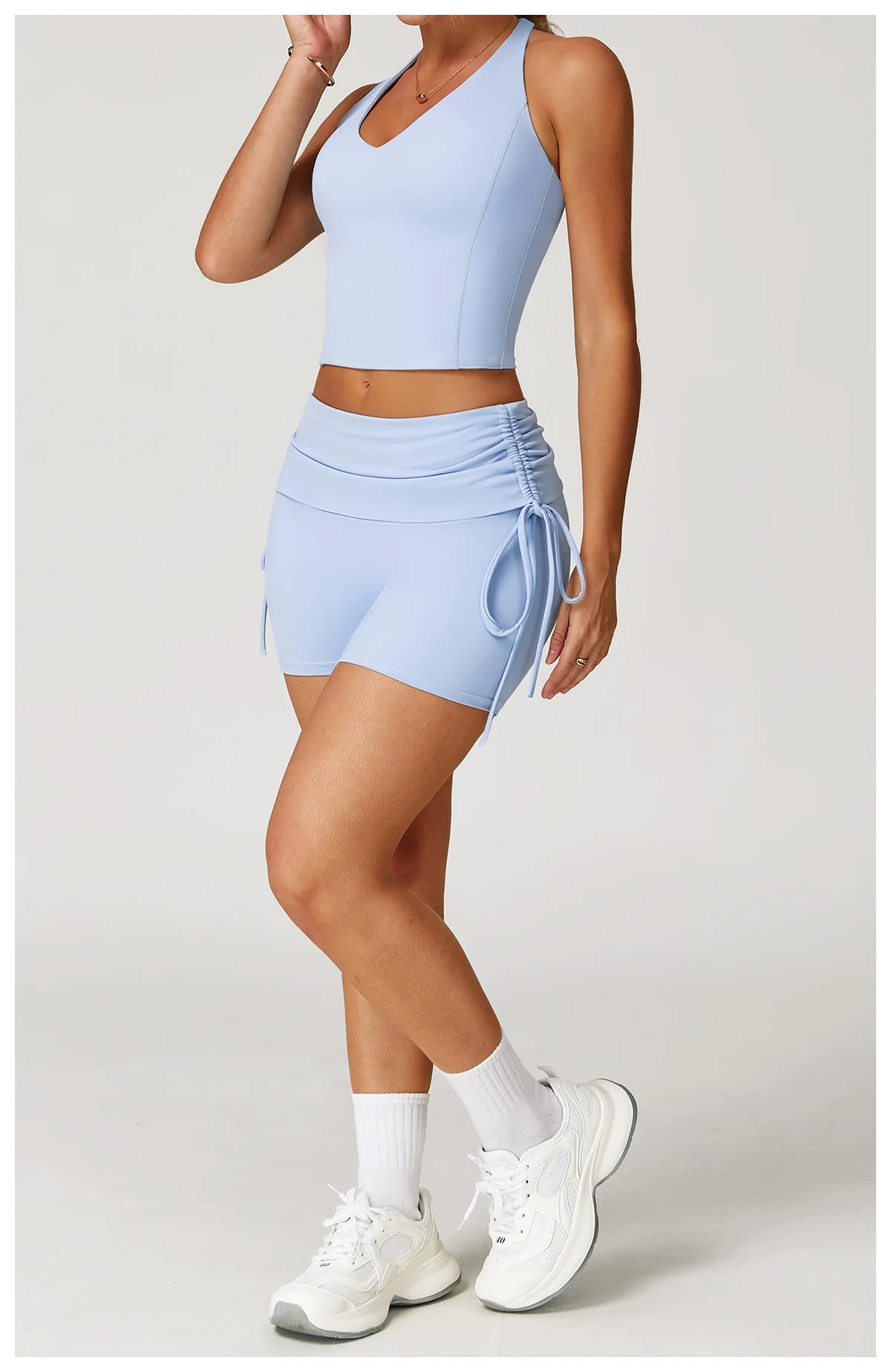 Person wearing a light blue athletic outfit with shorts and a top on a white background