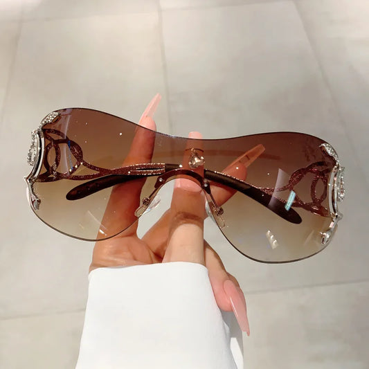 Sunglasses with decorative elements held by a hand against a light background